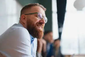 Smiling Bearded Man in Glasses at a Casual Business Meeting